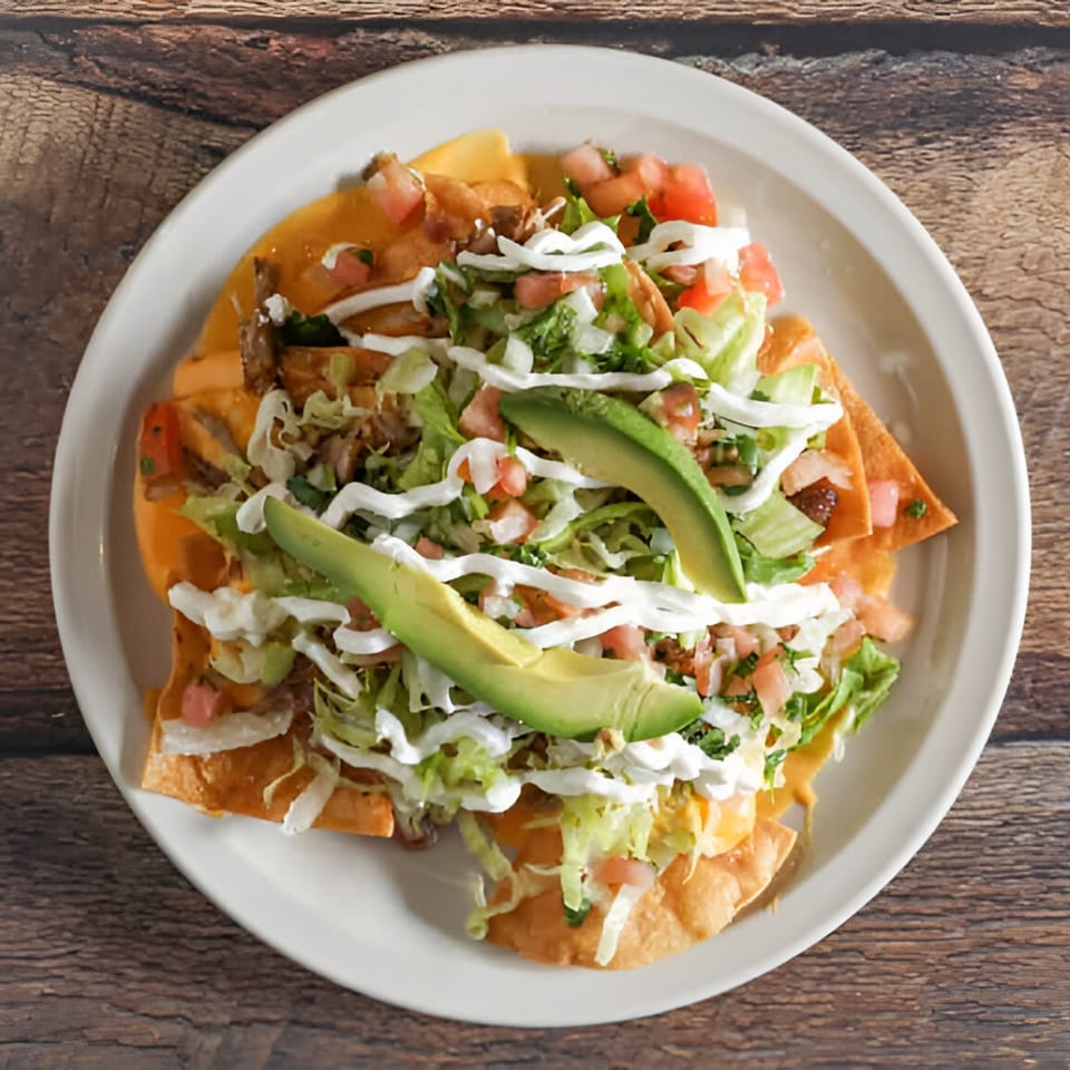Norma's Cocina nachos with chicken, cheese, lettuce, pico de gallo, sour cream, and avocado slices.