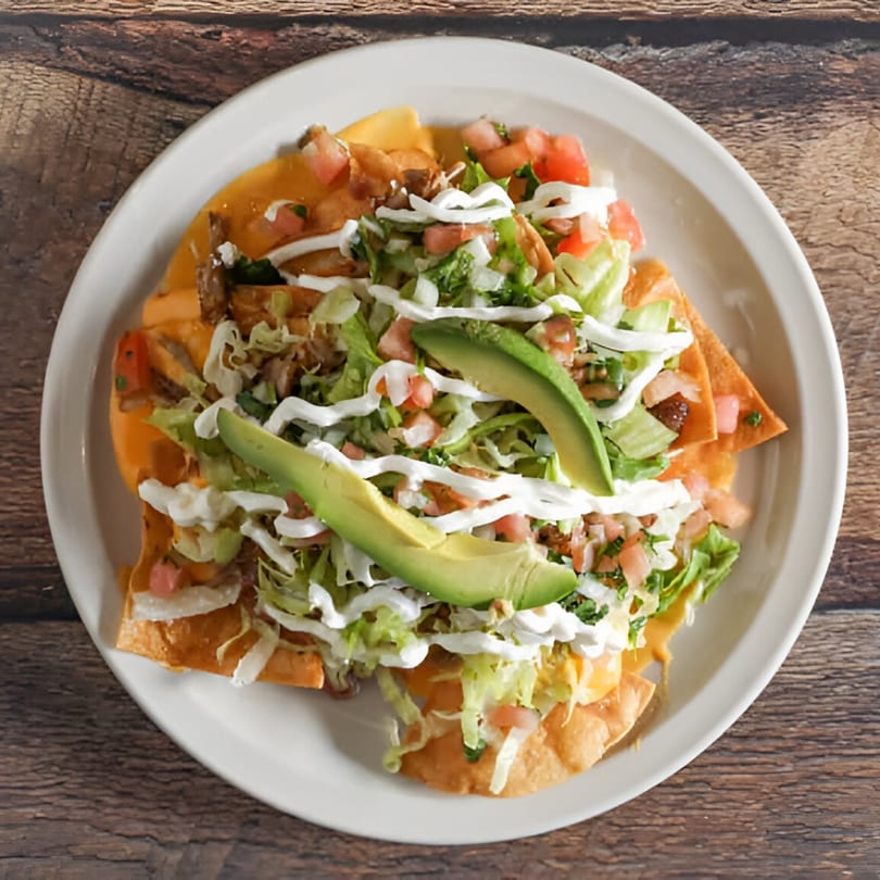 Norma's Cocina nachos with chicken, cheese, lettuce, pico de gallo, sour cream, and avocado slices.