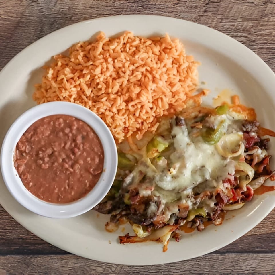 A plate of Norma's Cocina's Mexican food with rice, refried beans, and a cheesy meat dish.